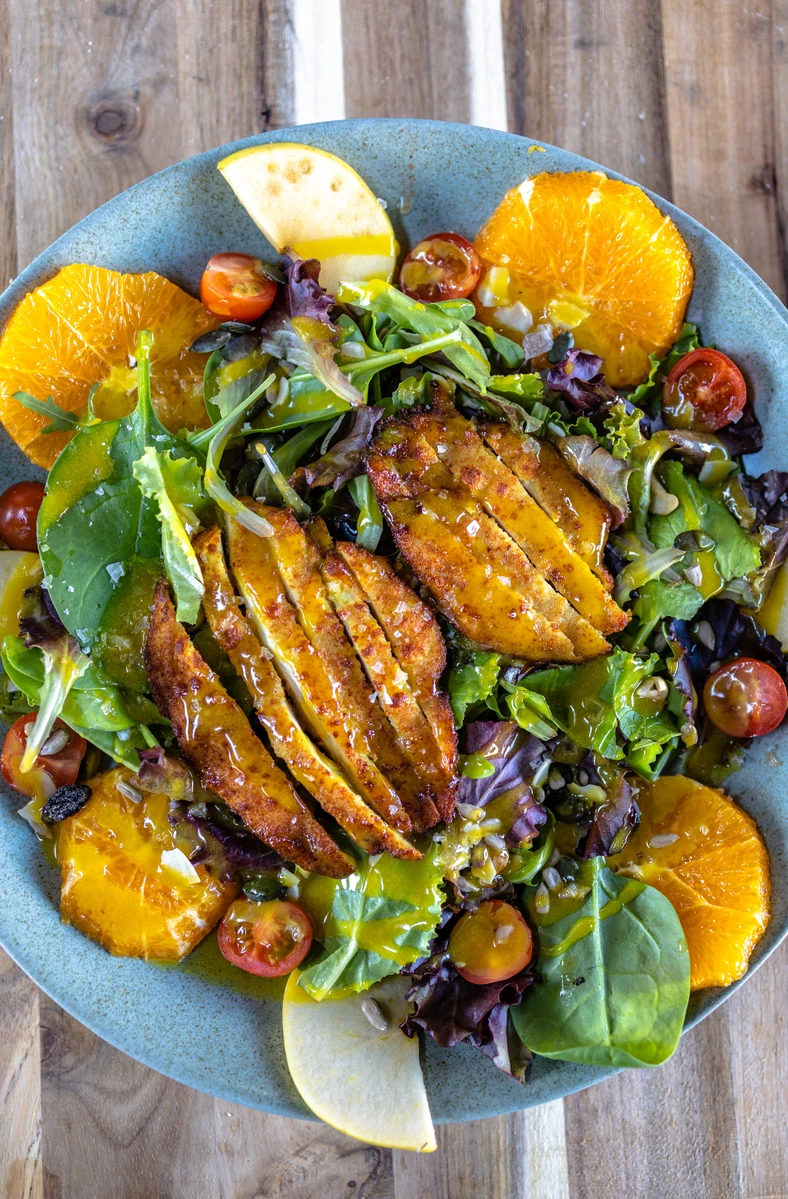 Ensalada de pollo crujiente, naranja, manzana verde, tomatitos cherry y frutos secos, con salsa de miel y mostaza casera